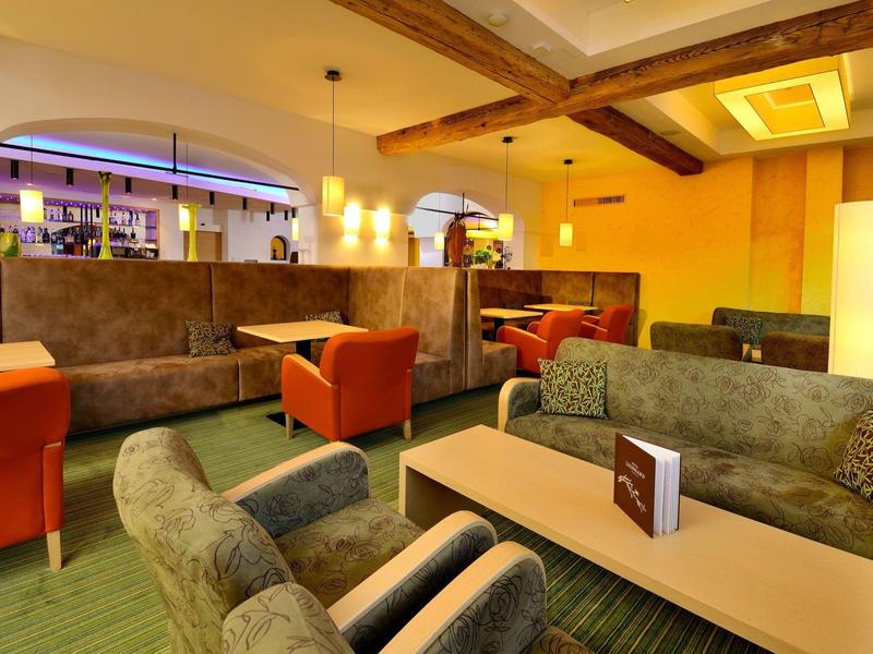 Modern eingerichteter Lounge-Bereich mit Sofas, Sesseln und warmer Beleuchtung in einem Hotel.