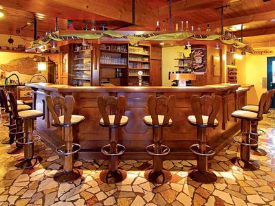 Bar rustica dell'hotel con bancone e sgabelli in legno su pavimento in pietra.