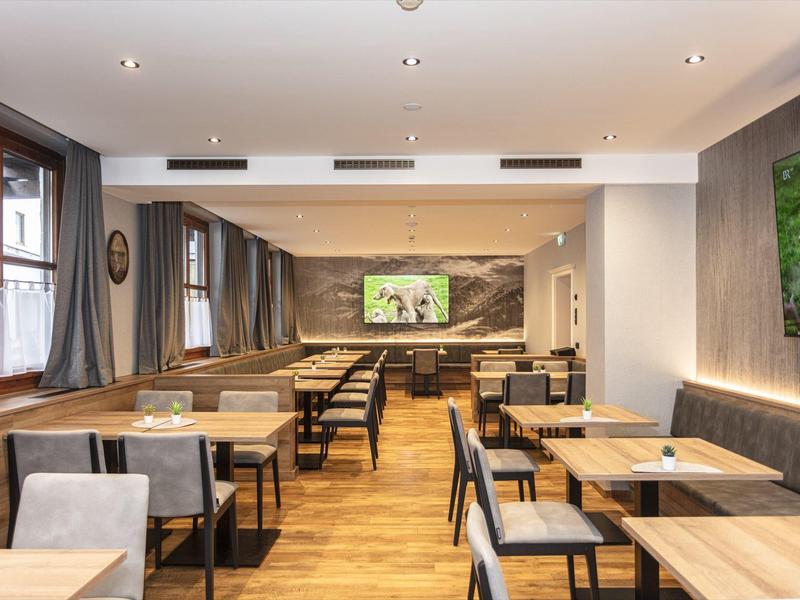 Salle à manger lumineuse avec meubles en bois et grande décoration murale.