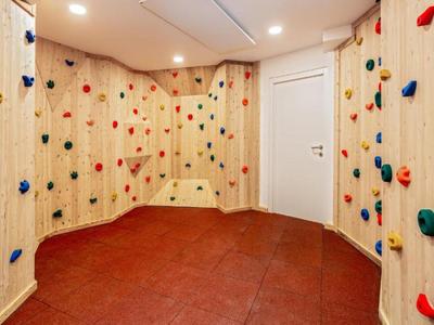 Sala de escalada con presas de colores y suelo antideslizante rojo en un hotel.
