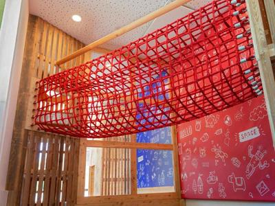 Túnel de juego colgado de red roja en habitación con paredes de colores y madera