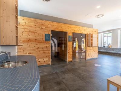 Zona de bienestar moderna con sauna de madera y suelo de baldosas grises en el hotel.