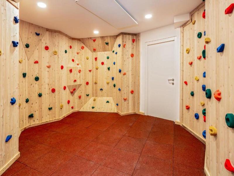 Sala de escalada con presas de colores y suelo antideslizante rojo en un hotel.