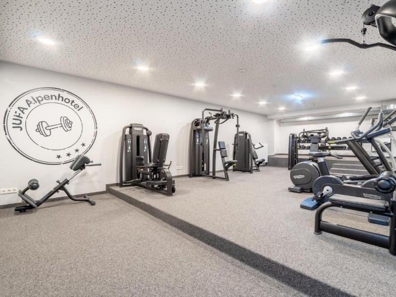 Gimnasio luminoso con varios equipos de ejercicio y colchonetas en diseño moderno.