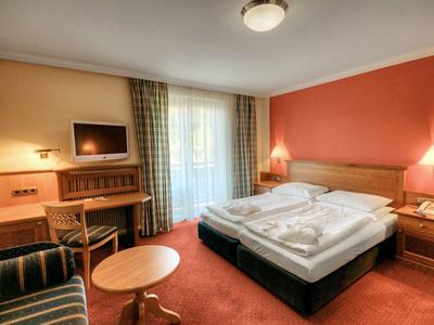 Cozy hotel room with double bed, seating area, desk, and TV.