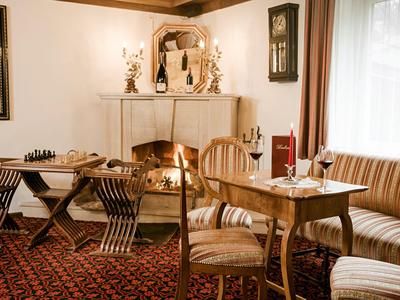 Area dell'hotel accogliente con camino, sedie, tavolo e gioco degli scacchi su tappeto.