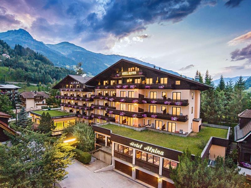 Hotel in the mountains with lit balconies and dramatic sky at dusk.