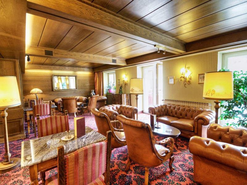 Elegant hotel lobby with wooden ceiling, comfortable leather armchairs, and carpeted floor.