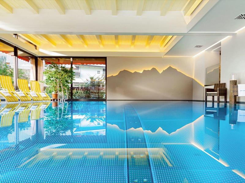 Indoor pool with yellow lounge chairs and mountain wall decor in the background.