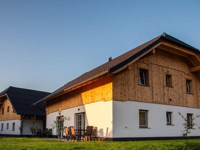 Venkovský rekreační dům se dřevěným obložením a bílým podstavcem pod jasnou večerní oblohou