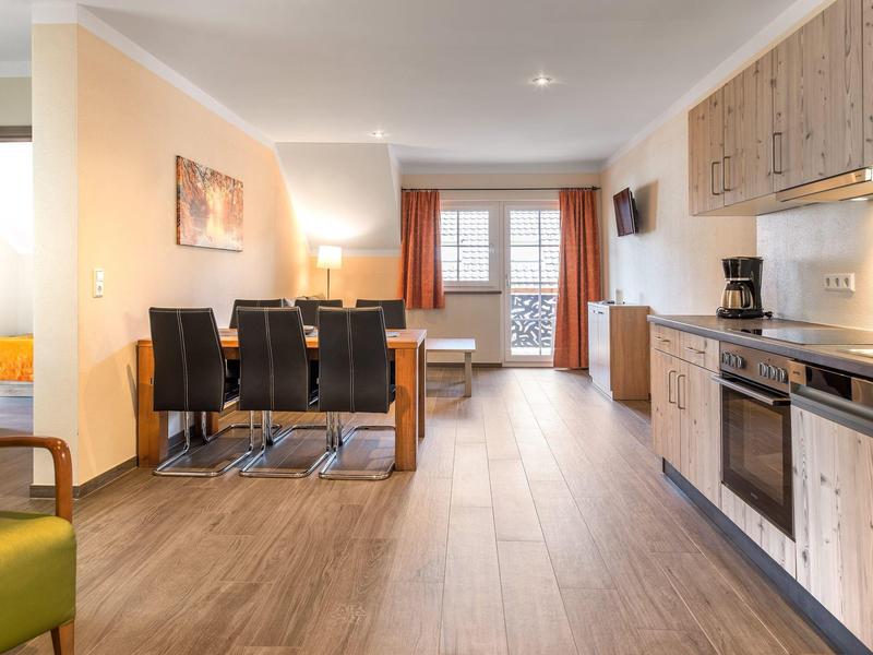 Moderně zařízený hotelový pokoj s kuchyní, jídelnou a balkonem s výhledem ven.