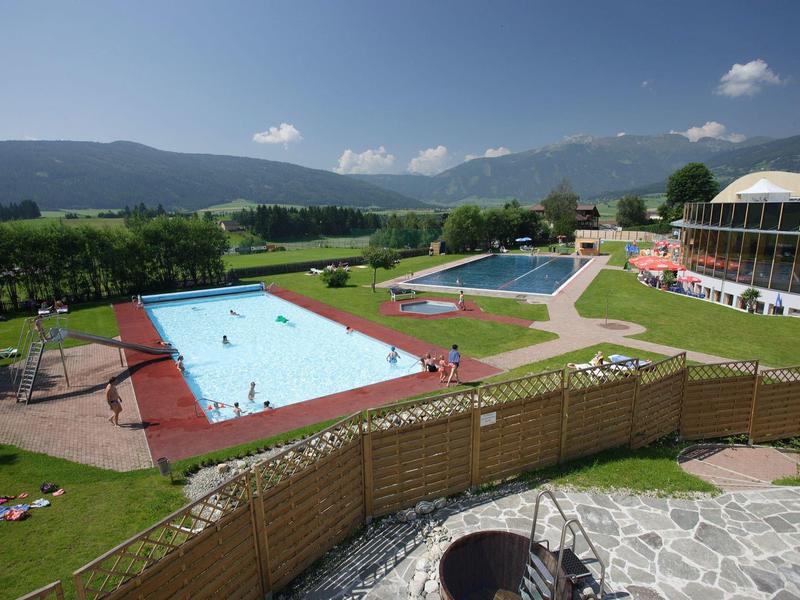 Rekreační areál s několika bazény na pozadí hor za slunečného dne.