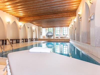 Intérieur d'une piscine couverte lumineuse avec plafond en bois et espace détente
