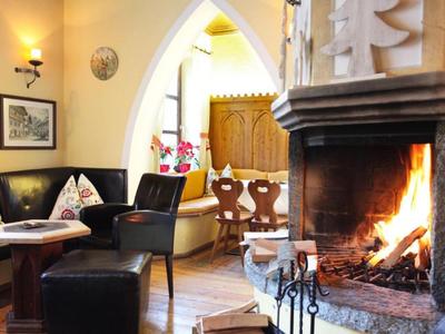 Accogliente lounge dell'hotel con camino acceso, sedute nere e tavoli di legno.