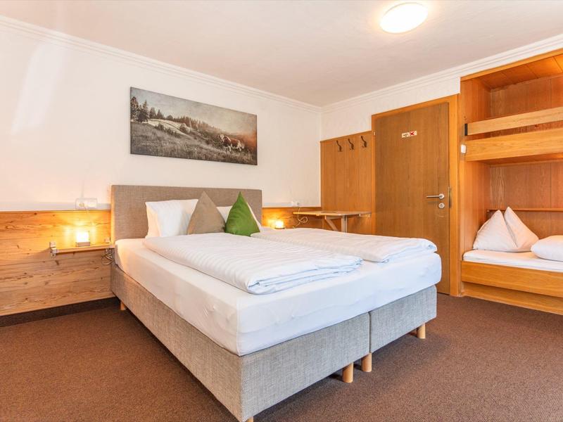 Chambre d'hôtel lumineuse avec lit double, lits superposés et armoires en bois