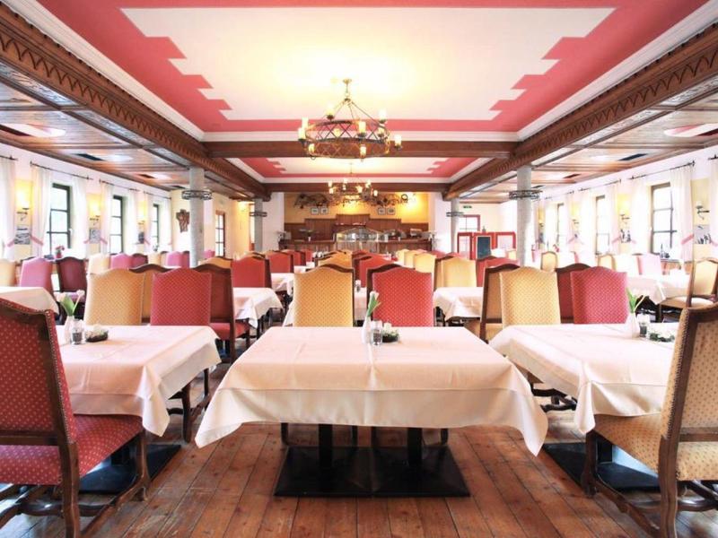 Grande salle à manger traditionnelle avec tables dressées et chaises aux couleurs chaudes.