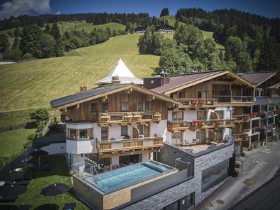 Hotel alpino con piscine e colline verdi sullo sfondo.