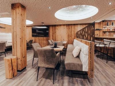 Pohodlná hotelová společenská místnost s dřevěnými stěnami a moderním nábytkem.