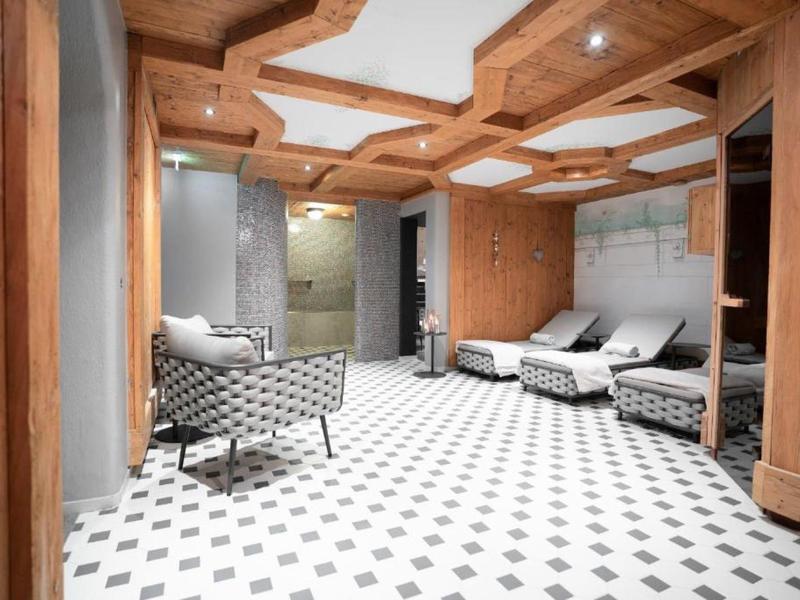 Elegantní odpočinková místnost s dřevěným stropem, pohodlnými křesly a přilehlou koupelnou.