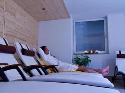 Osoba relaksująca się w szlafroku na leżaku w nowoczesnym pokoju spa z światłem świec.