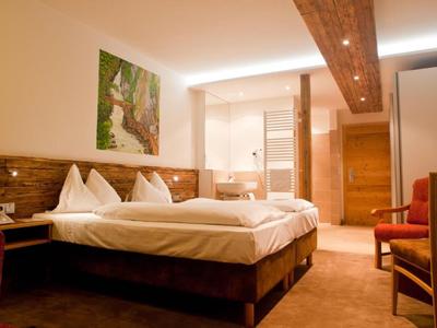 Gemütliches Hotelzimmer mit Doppelbett, Holzdecke und moderner Beleuchtung.