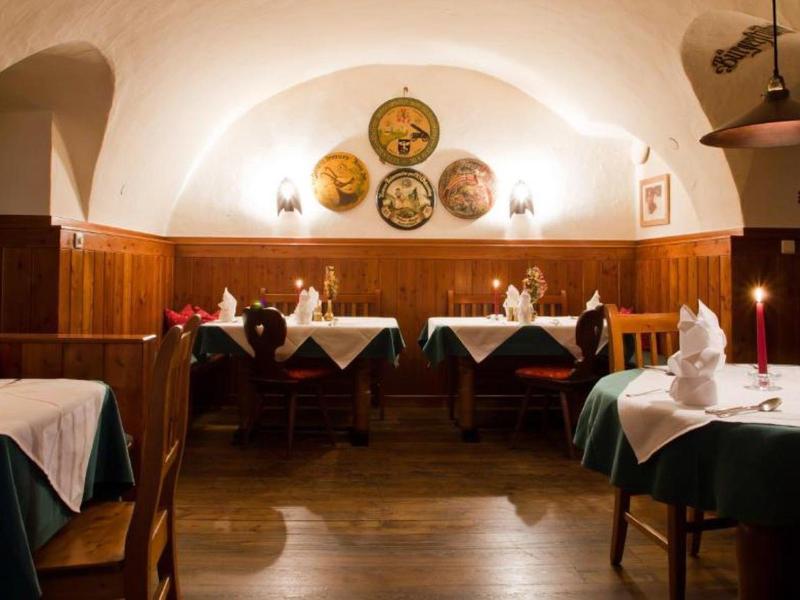 Przytulna jadalnia z nakrytymi stołami, białą zastawą i światłem świec w ciepłej atmosferze.