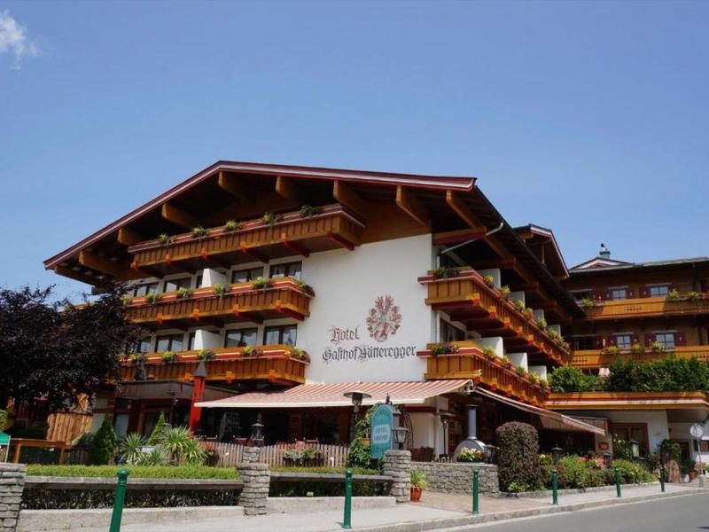 Duży tradycyjny hotel z drewnianymi balkonami i kwiatowymi ozdobami pod błękitnym niebem.