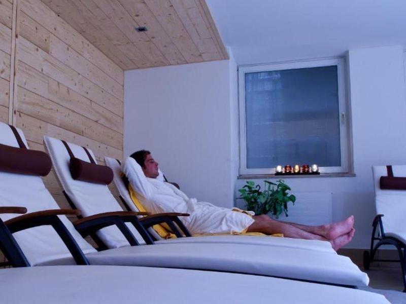 Osoba relaksująca się w szlafroku na leżaku w nowoczesnym pokoju spa z światłem świec.