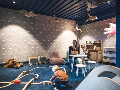 Kinderspielzimmer mit Kletterwand, Spielzeug und Sitzgelegenheiten in einem Hotel.