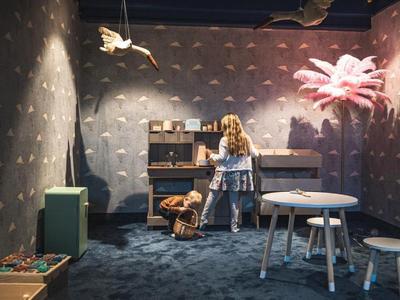 Kind spielt in einem dunklen Raum mit einem Spielzeugküche und bunten Möbeln.