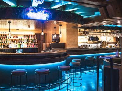 Moderner Barbereich mit beleuchtetem Tresen und Hockern in einer stilvollen Atmosphäre.