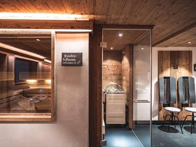 Moderner Wellnessbereich mit Sauna und entspannenden Sitzplätzen in warmem Licht.