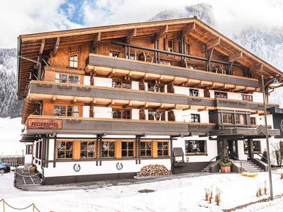 Traditionelles Chalet-Hotel mit Holzfassade und Schnee im Vordergrund