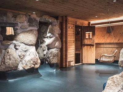 Innenraum eines Wellnessbereichs mit Steinwand, Holzverkleidung und Wasserbecken.