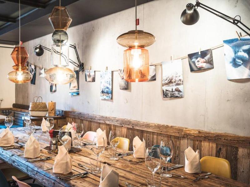 Rustikaler Esstisch mit blauen Stühlen und modernen Hängelampen in einem Restaurant.