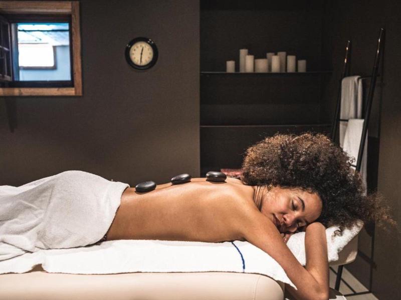 Frau entspannt sich bei Hot-Stone-Massage in ruhigem Spa-Zimmer.