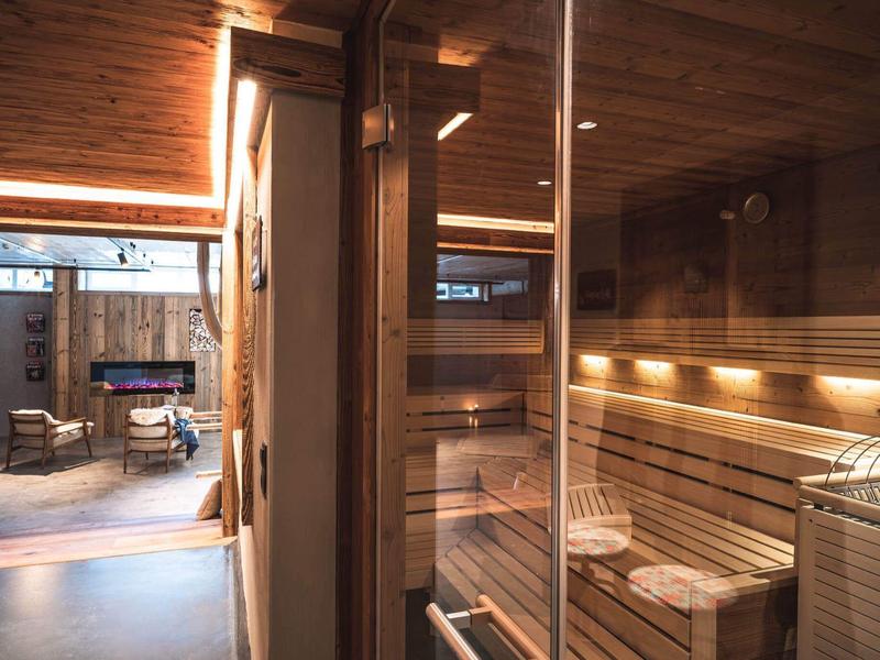 Ein moderner Saunabereich mit Holzinterieur und Sitzbänken neben einem hell beleuchteten Entspannungsraum.