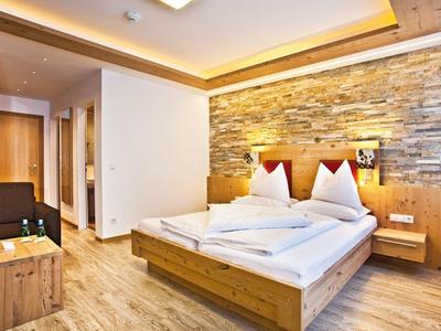 Moderne hotelkamer met tweepersoonsbed, houten meubels en verlichte stenen muur op de achtergrond