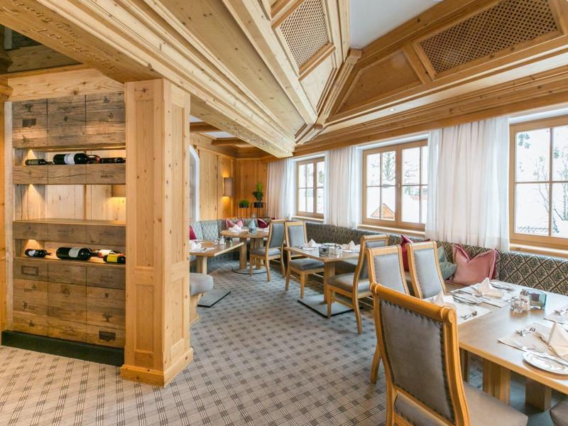 Gezellig houten restaurantgedeelte met tafels en stoelen naast grote ramen.