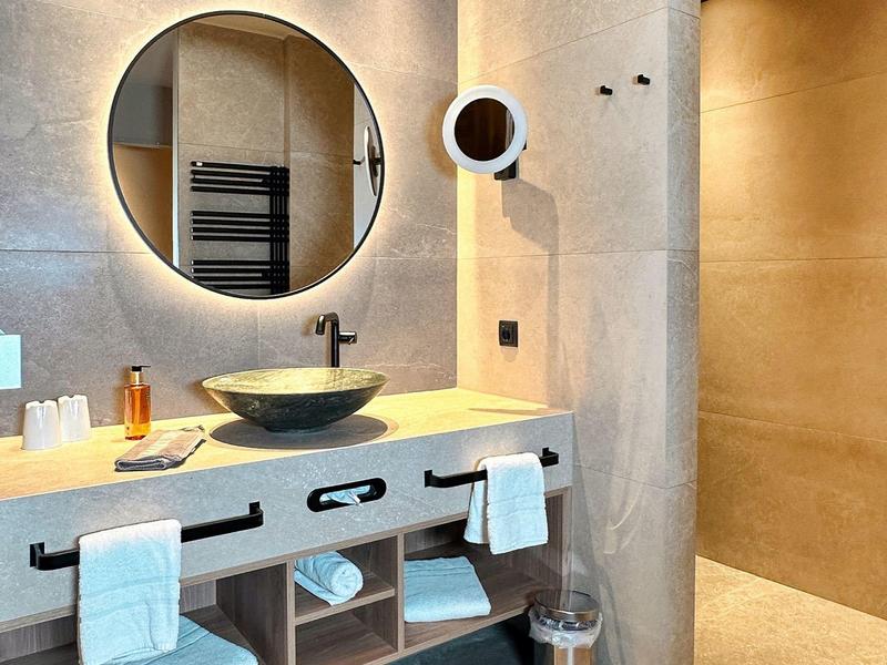 Moderne badkamer met grote ronde spiegel, wastafel en handdoeken onder het aanrecht.