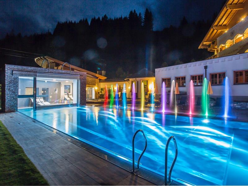 Luxe zwembad met kleurrijke waterfonteinen en moderne verlichting 's nachts.