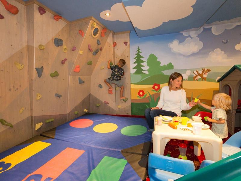 Een kleurrijke speelkamer voor kinderen met een klimwand, speeltafel en tapijt met wegontwerp.