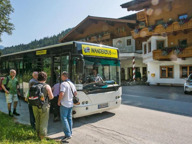 Mensen stappen in een stadsbus bij een bushalte in een bergachtig gebied.