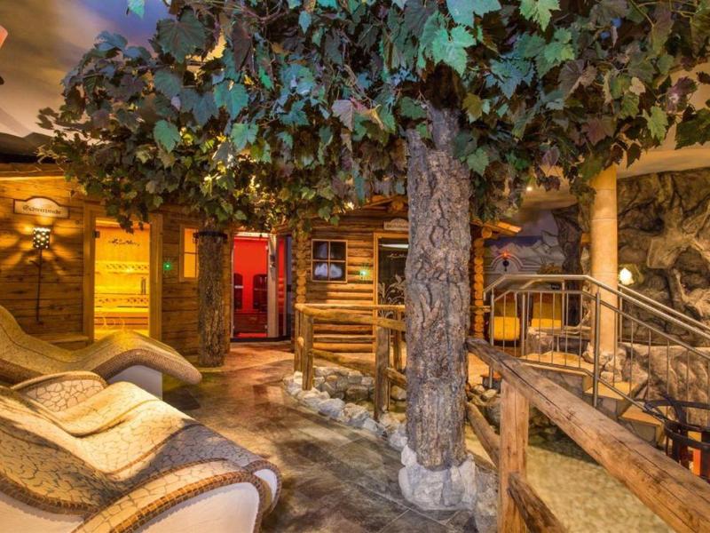 Gezellig wellnessgedeelte met ligstoelen en rustiek houten interieur onder een kunstmatig bladerdak.