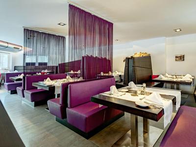 Ristorante moderno con cabine imbottite viola e tavoli elegantemente apparecchiati.