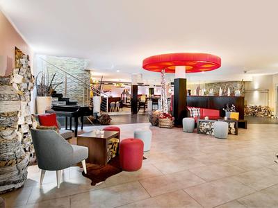 Helle Hotellobby mit gemütlichen Sitzbereichen, Kunstobjekten und moderner Dekoration.