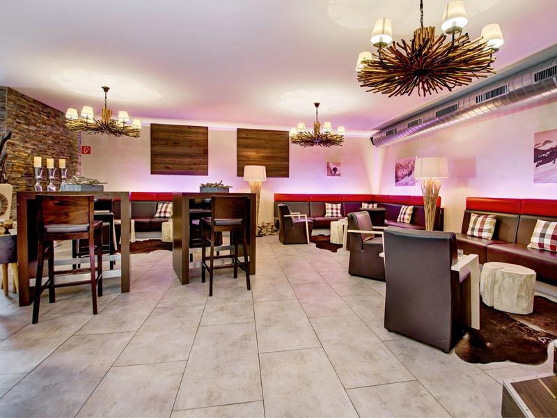 Zona de salón moderna del hotel con varias opciones de asientos e iluminación brillante.