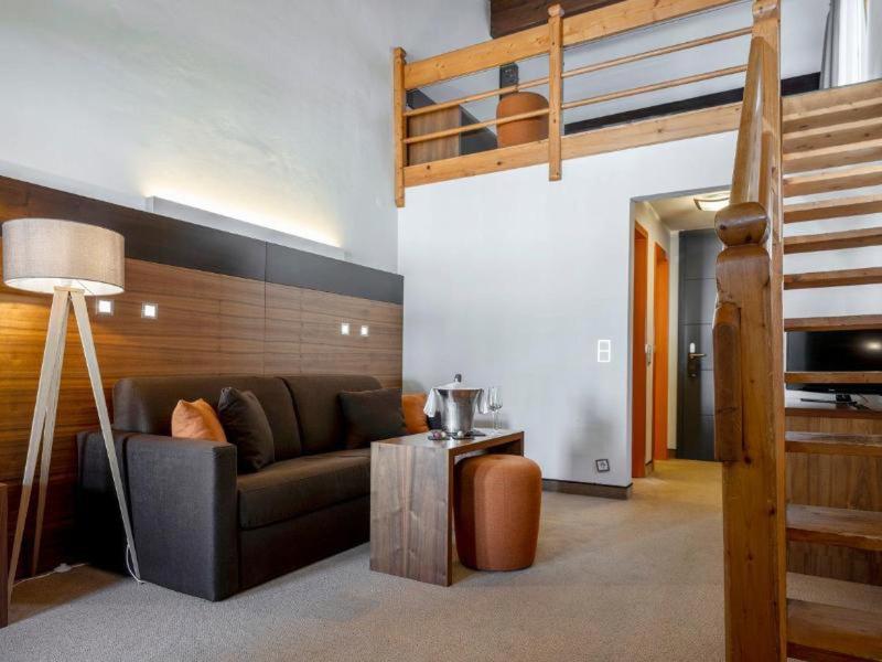 Sala moderna con sofá de cuero, escalera de madera y iluminación acogedora.