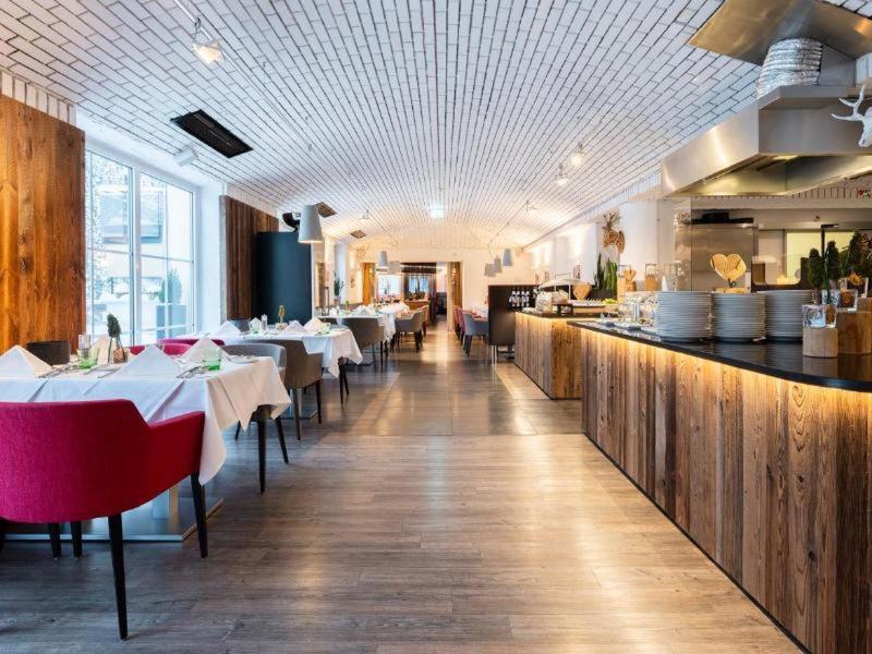 Restaurante moderno de hotel con acentos de madera, sillas rojas y mesas preparadas en un ambiente luminoso