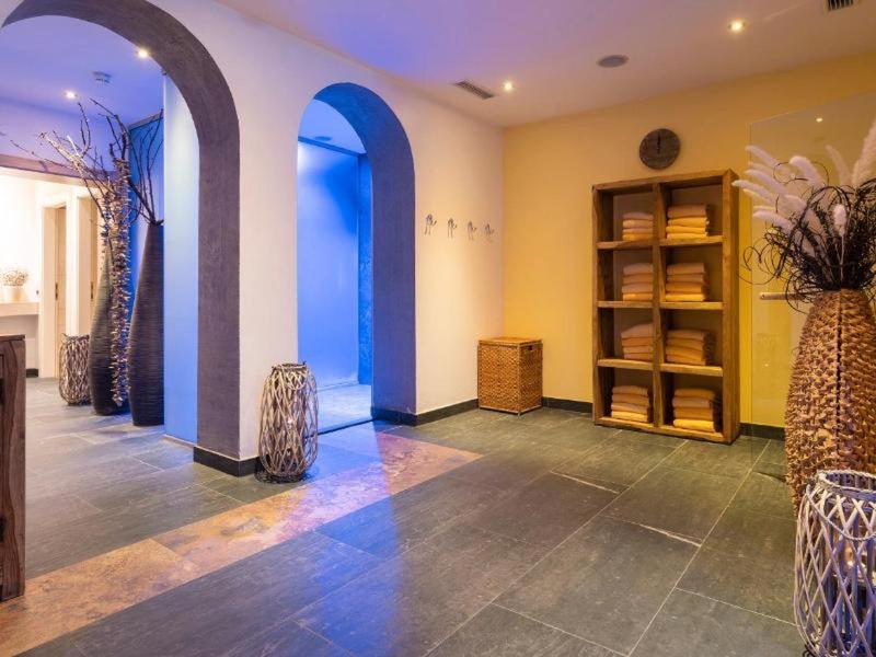 Pasillo con varios arcos redondeados, estantes y elementos decorativos con luz cálida.